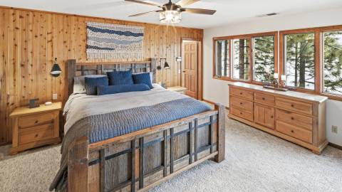Una foto de una cabaña en Destination Big Bear: hay una cama grande y cómoda, una cómoda y una mesita de noche, y ventanas.