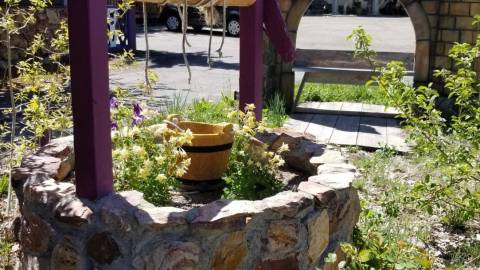 Una foto de la entrada a Castle Wood Cottages: hay un pozo de los deseos y un arco de castillo.