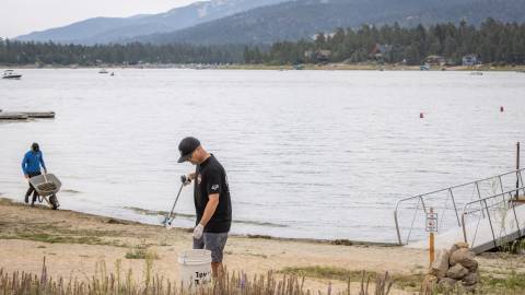 Dos voluntarios recorren las orillas del lago Big Bear en busca de basura que recoger, como parte de la iniciativa «Care For Big Bear».