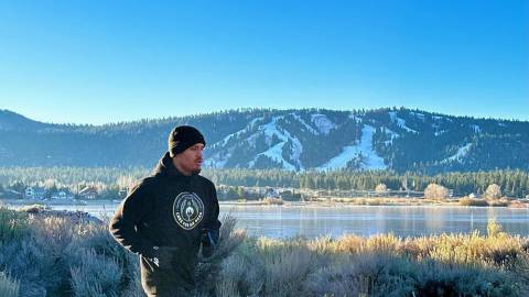 El boxeador profesional Ronaldo Mancilla hace footing por una carretera de Big Bear Lake, California, con el lago y las montañas a sus espaldas.