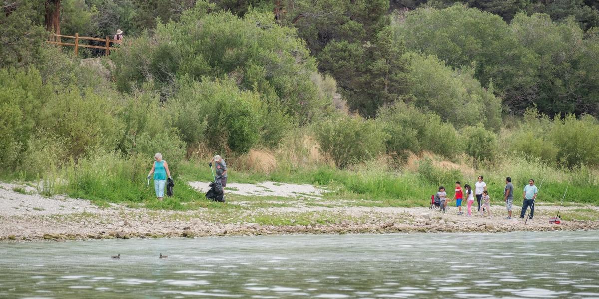 Un par de voluntarios en la orilla del lago recogiendo basura con sus pinzas para Care For Big Bear.