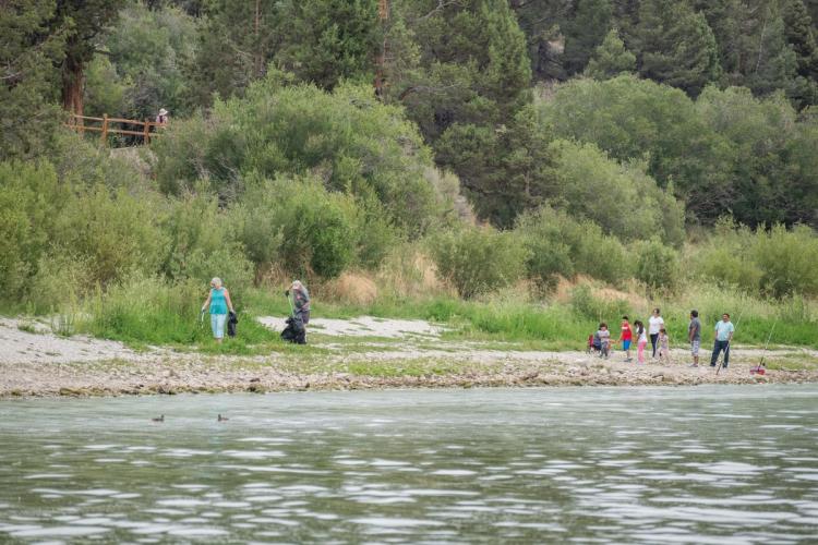 Un par de voluntarios en la orilla del lago recogiendo basura con sus pinzas para Care For Big Bear.