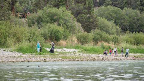 Un par de voluntarios en la orilla del lago recogiendo basura con sus pinzas para Care For Big Bear.