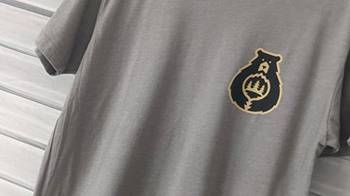 Una camiseta gris con el logotipo de Care For Big Bear, la camiseta está en un expositor de ropa