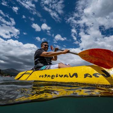 Un hombre sonríe mientras rema en un kayak amarillo en el lago Big Bear.