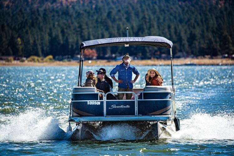 Un grupo de turistas sonríe en un paseo en pontón por el lago Big Bear
