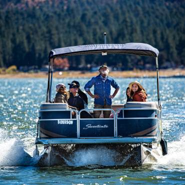 Un grupo de turistas sonríe en un paseo en pontón por el lago Big Bear