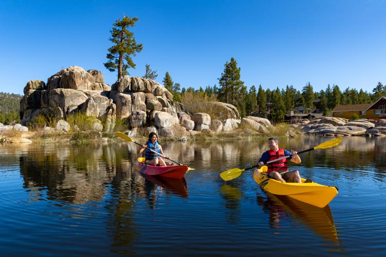 Un hombre en un kayak amarillo y una mujer en un kayak rojo en Big Bear Lake en un soleado día de verano
