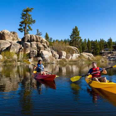 Un hombre en un kayak amarillo y una mujer en un kayak rojo en Big Bear Lake en un soleado día de verano