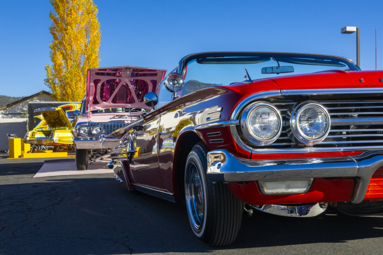 Varios lowriders alineados uno tras otro alejándose del espectador durante el Lowrider Kickback en el Centro de Visitantes de Big Bear