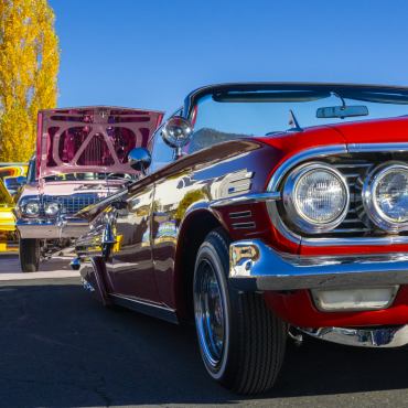 Varios lowriders alineados uno tras otro alejándose del espectador durante el Lowrider Kickback en el Centro de Visitantes de Big Bear