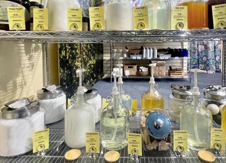A metal shelf features shampoos and detergents in glass containers at Chirp Nature Centers.
