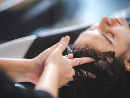 A photo of a lady having her hair washed at a salon, the barber's fingers massaging her scalp.