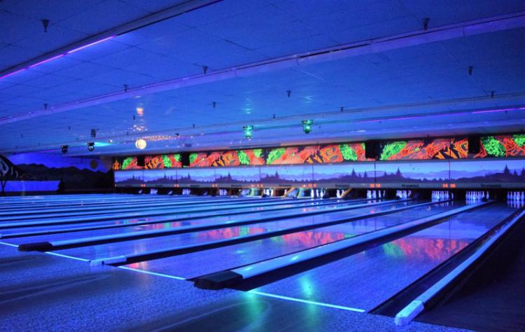 Luces de neón azules iluminan las pistas interiores de la bolera Big Bear Bowling Barn durante los eventos de bolos brillantes.