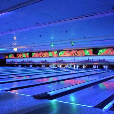 Luces de neón azules iluminan las pistas interiores de la bolera Big Bear Bowling Barn durante los eventos de bolos brillantes.