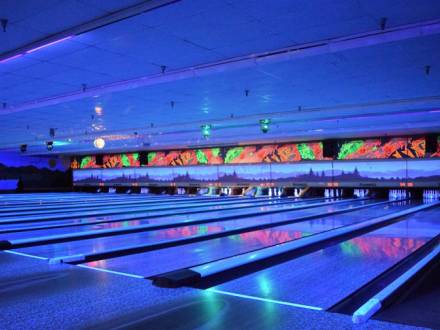 Luces de neón azules iluminan las pistas interiores de la bolera Big Bear Bowling Barn durante los eventos de bolos brillantes.