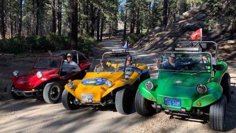 Tres buggies alineados en una pista de tierra off road, las personas que van dentro posan para una foto.