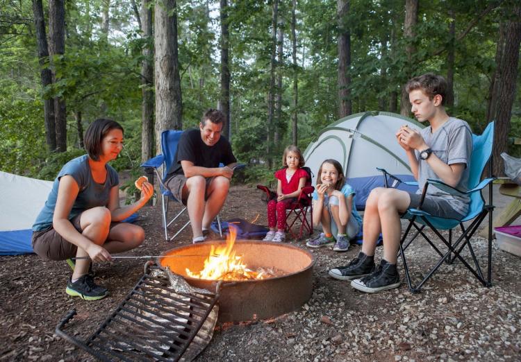 Una familia pasa tiempo junta y asa comida en una hoguera en Big Bear, California. Un bosque verde rodea su campamento.