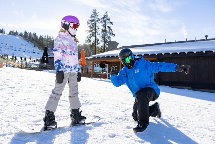 Un instructor guía a un alumno sobre una tabla de snowboard en la estación de esquí Snow Summit de Big Bear Lake, California.