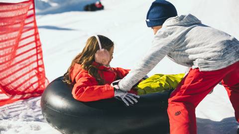 Un niño empuja a un amigo en un tubo de nieve durante un juego en Big Bear Lake, CA.
