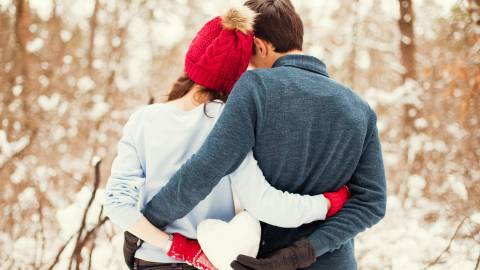 una pareja sostiene una bola de nieve de corazón en Big Bear, CA