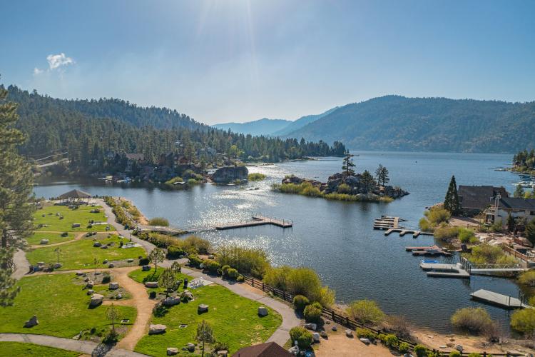 Una toma aérea con dron del parque Boulder Bay en Big Bear Lake. El agua resplandeciente toca la orilla verde brillante.