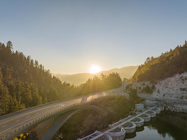 El sol se pone sobre la presa de Big Bear y el puente de la carretera en otoño.