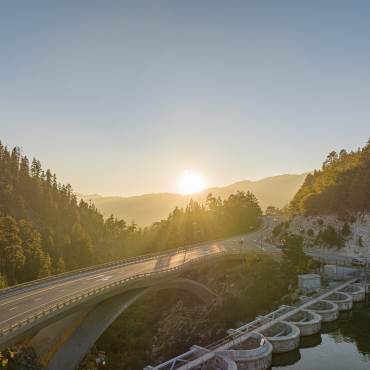 El sol se pone sobre la presa de Big Bear y el puente de la carretera en otoño.