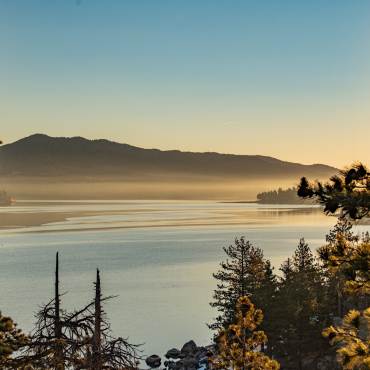 Una foto tomada durante una hora dorada en Big Bear Lake, la niebla y el agua del lago reflejando suavemente la luz dorada.