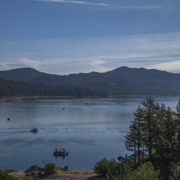 Una foto del lago Big Bear, hay muchos barcos en el agua, los árboles y las montañas se ven a lo lejos.