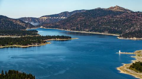 Una vista aérea del lago Big Bear. Es un día soleado, con cielos azules despejados y verdes pinares rodean el lago azul.