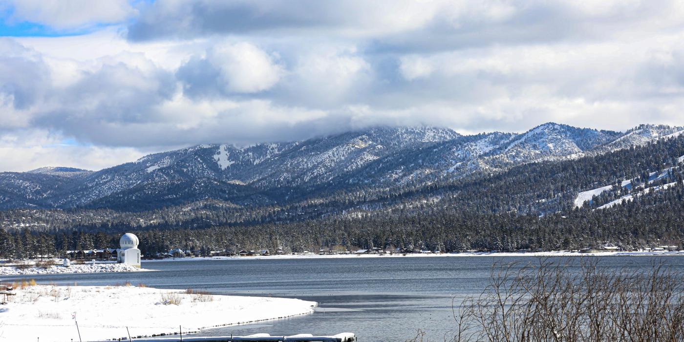Una foto del lago Big Bear durante el invierno, el suelo cubierto de nieve fresca y el observatorio visible en la distancia.