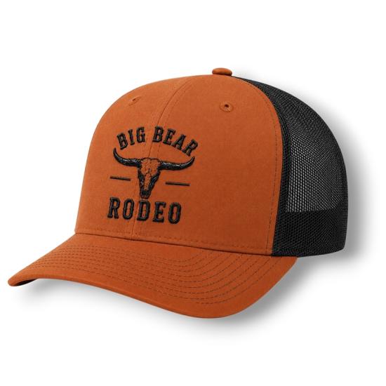 Un sombrero de rodeo naranja vendido durante el Rodeo de Big Bear Lake; tiene una pegatina con un animal de cuernos largos y, debajo, la inscripción «Big Bear Rodeo».