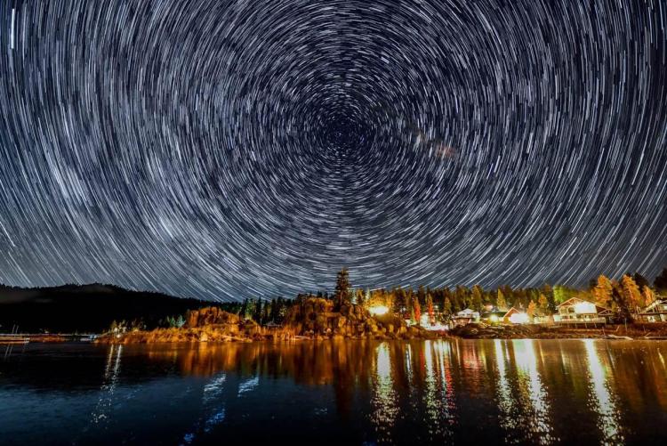 Un timelapse de estrellas en círculo en el cielo nocturno sobre Boulder Bay en Big Bear Lake, CA.