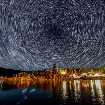 Un timelapse de estrellas en círculo en el cielo nocturno sobre Boulder Bay en Big Bear Lake, CA.