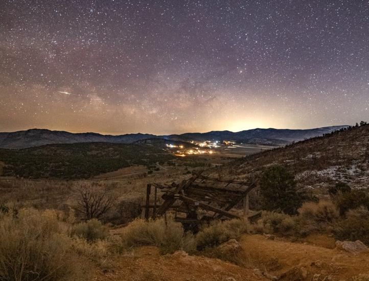 Una imagen de las estrellas y la Vía Láctea en el cielo nocturno sobre Big Bear. En primer plano se ve un antiguo pozo minero.