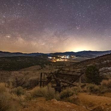 Una imagen de las estrellas y la Vía Láctea en el cielo nocturno sobre Big Bear. En primer plano se ve un antiguo pozo minero.