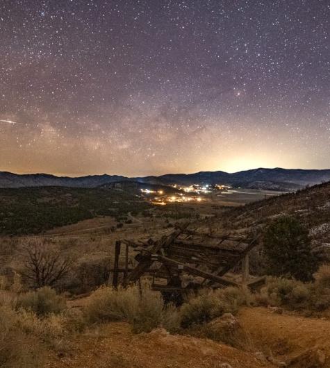 Una imagen de las estrellas y la Vía Láctea en el cielo nocturno sobre Big Bear. En primer plano se ve un antiguo pozo minero.