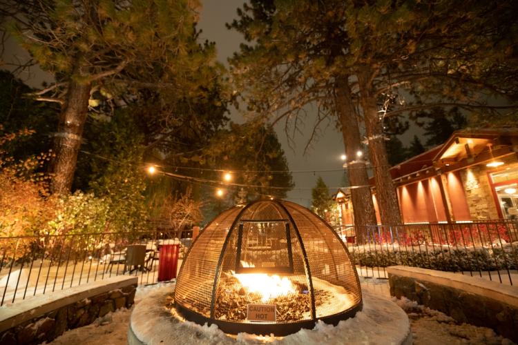 Una foto de una hoguera en Big Bear Lake Village durante el invierno: hay algo de nieve en el suelo y alrededor de la hoguera.