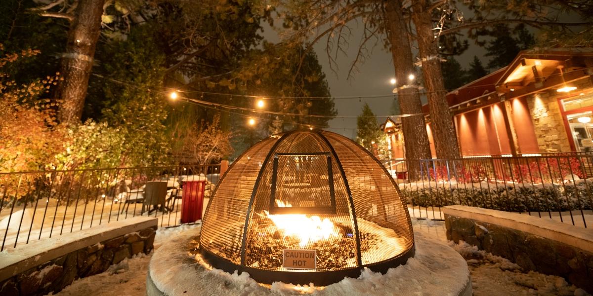 Una foto de una hoguera en Big Bear Lake Village durante el invierno: hay algo de nieve en el suelo y alrededor de la hoguera.