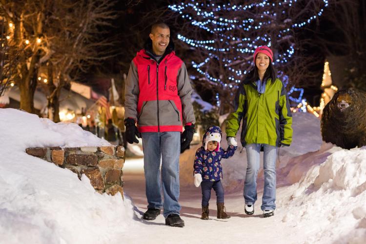 Una familia pasea por The Village en Big Bear Lake en invierno. La nieve les rodea.