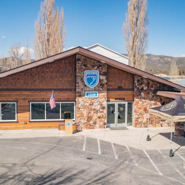 Fachada del Centro de Visitantes de Big Bear Lake en verano. El logotipo del oso azul destaca entre la piedra natural