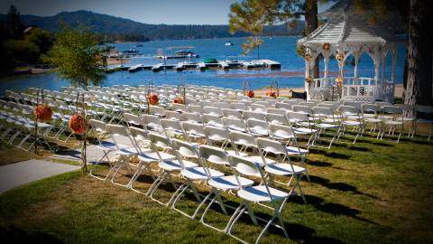 Filas de sillas blancas y un altar bajo un cenador junto al lago Big Bear Lake.