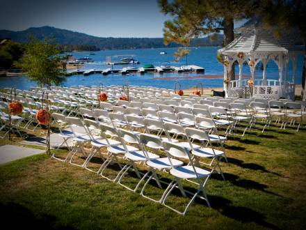 Filas de sillas blancas y un altar bajo un cenador junto al lago Big Bear Lake.
