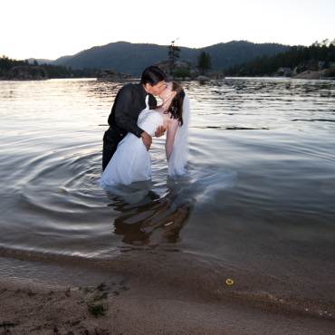 Unos novios comparten un beso durante su ceremonia de boda mientras vadean el lago Big Bear.