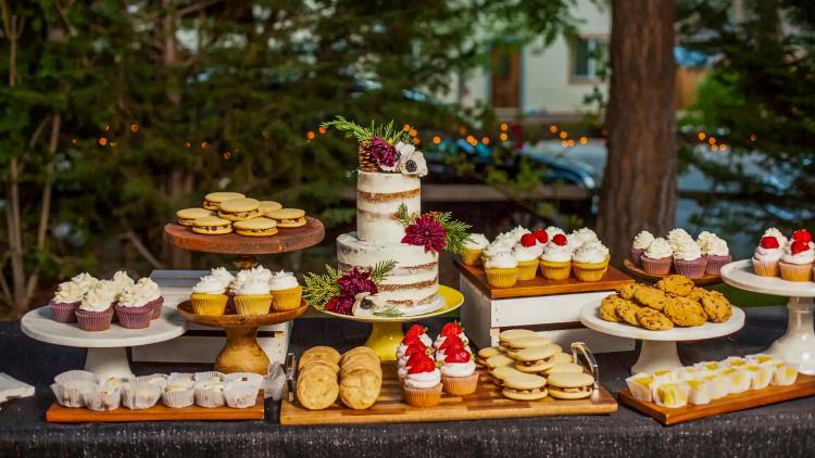Una foto de los postres de boda de Sister My Sister Bake Shop: se ve una tarta de boda de dos pisos rodeada de diversos postres.