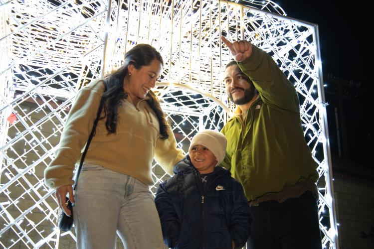Foto de una familia de tres miembros delante de una pantalla de luces en el evento Wild Zoo Alpine Lights, el padre está señalando.