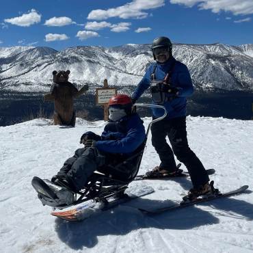 Dos esquiadores se preparan para bajar por las pistas de Bear Mountain; uno de ellos utiliza esquís adaptados.
