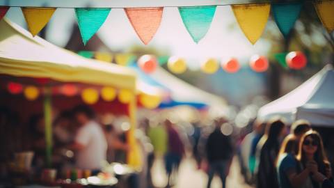 An out of focus market faire with vendor's easy ups and people walking around visible in the background