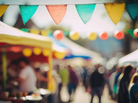 Un mercado de feria desenfocado en el que se ve al fondo a los vendedores y a la gente paseando.